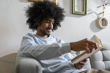 Smiling man reading book at home - VPIF08208