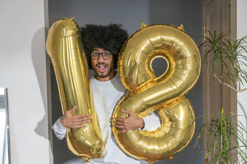 Surprise man holding 18 number balloon at home - VPIF08223