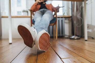 Young man with legs crossed over hardwood floor at home - VPIF08242