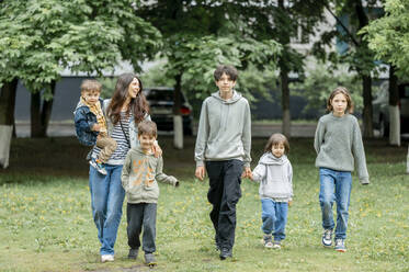 Glückliche Mutter geht mit Kindern im Park spazieren - ANAF01476