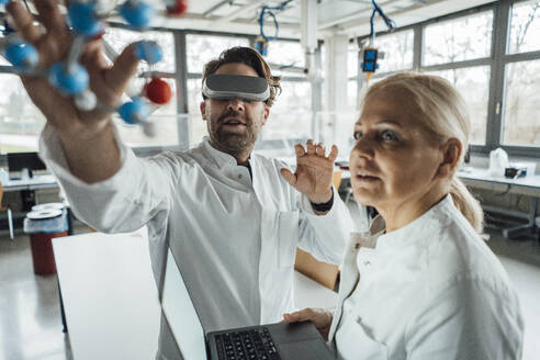Wissenschaftlerin trägt Virtual-Reality-Simulator und untersucht mit einem Kollegen die Molekularstruktur - JOSEF19561