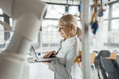 Lächelnder leitender Wissenschaftler mit Laptop im Labor - JOSEF19562