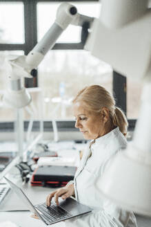 Wissenschaftlerin benutzt Laptop mit Roboterarmen im Labor - JOSEF19575