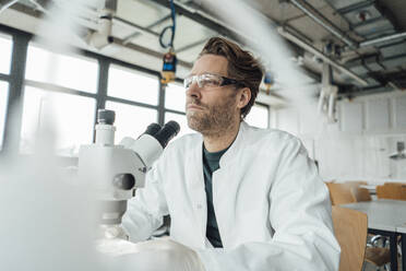 Contemplative mature scientist with microscope - JOSEF19602