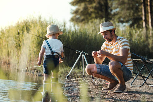 Ein reifer Vater mit einem kleinen Sohn im Kleinkindalter beim Angeln an einem Fluss oder See. - HPIF20201