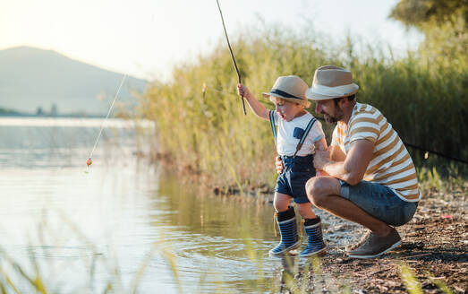 Ein reifer Vater mit einem kleinen Sohn im Kleinkindalter beim Angeln an einem Fluss oder See. - HPIF20202
