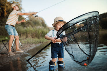 Baby boy wearing raincoat and life jacket while holding fishing