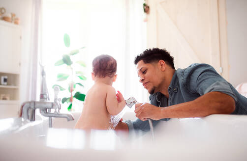 Hispanischer Vater wäscht seinen kleinen Sohn in einem Badezimmer zu Hause. - HPIF20239