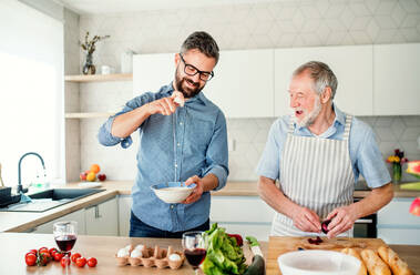 Ein erwachsener Hipster-Sohn und ein älterer Vater in der Küche zu Hause beim Kochen. - HPIF20277