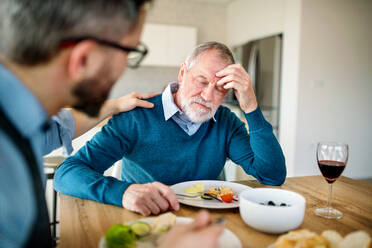 Ein erwachsener Hipster-Sohn tröstet einen frustrierten älteren Vater zu Hause bei einem leichten Mittagessen. - HPIF20305