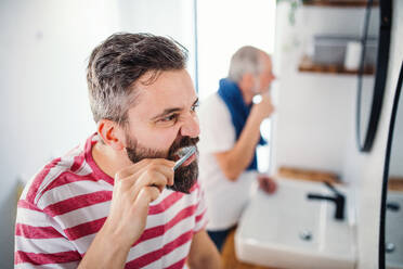 Ein erwachsener Hipster-Sohn und ein älterer Vater beim Zähneputzen im heimischen Badezimmer. - HPIF20331