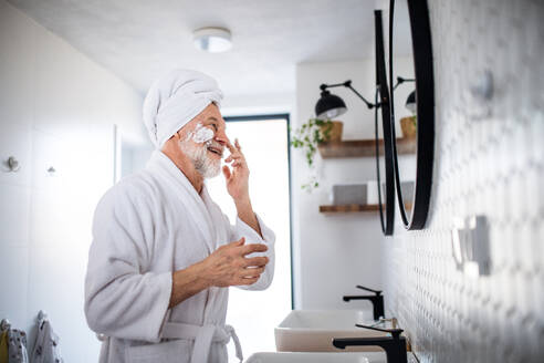 Ein älterer Mann, der seine morgendliche Routine im Badezimmer zu Hause erledigt und in den Spiegel schaut. - HPIF20337