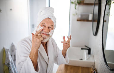 Ein älterer Mann bei der morgendlichen Routine im Badezimmer zu Hause, der in die Kamera schaut. - HPIF20338