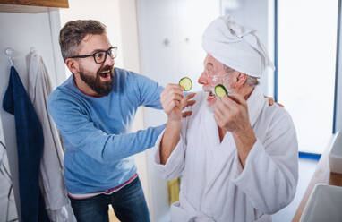 Ein fröhlicher erwachsener Hipster-Sohn und ein älterer Vater im Badezimmer zu Hause, die Spaß haben. - HPIF20350