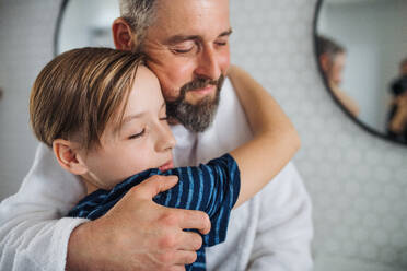 Ein reifer Vater mit seinem kleinen Sohn, der sich morgens im Badezimmer umarmt. - HPIF20388
