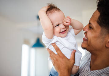 Ein Porträt eines fröhlichen Vaters und eines Kleinkindes, das zu Hause spielt. - HPIF20410