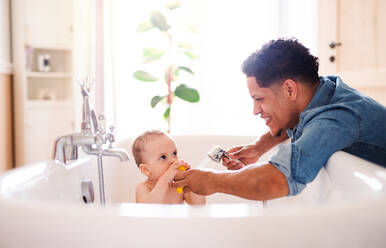 Hispanic father washing small toddler son in a bathroom indoors at home. - HPIF20418