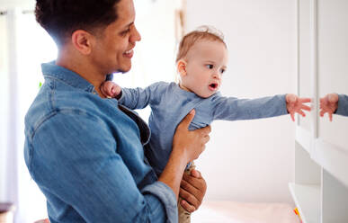 Ein Porträt eines fröhlichen Vaters und eines Kleinkindes, das zu Hause spielt. - HPIF20423