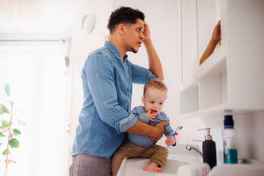 Young father and small toddler son in a bathroom indoors at home, washing. - HPIF20424