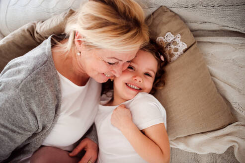 Ein Porträt eines kleinen Mädchens mit Großmutter, die sich zu Hause amüsieren, von oben gesehen. - HPIF20472