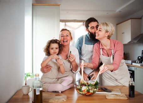 Porträt eines kleinen Mädchens mit Eltern und Großmutter zu Hause bei der Zubereitung von Gemüsesalat. - HPIF20561