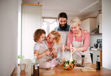 A portrait of small girl with parents and grandmother at home, preparing vegetable salad. - HPIF20562