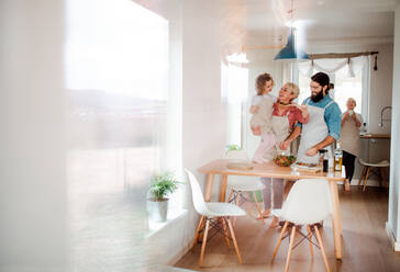 A portrait of small girl with parents and grandmother at home, preparing vegetable salad. - HPIF20564