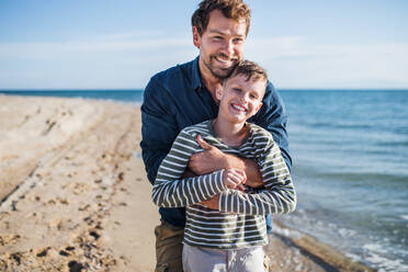 Vater mit kleinem Sohn umarmt auf einem Spaziergang im Freien am Strand, Spaß haben. - HPIF20654