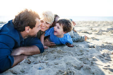 Porträt einer jungen Familie mit zwei kleinen Kindern, die im Freien am Strand liegen und sich amüsieren. - HPIF20662