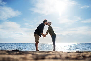 A young couple standing outdoors on beach, kissing. Copy space. - HPIF20673