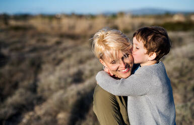 Young mother with small daughter standing in mediterranean nature, kissing. - HPIF20677