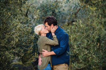 Ein junges, verliebtes Paar steht im Freien in einem Olivenhain und küsst sich. - HPIF20690