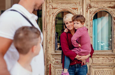 A midsection of young family with two small children walking outdoors in town. - HPIF20696