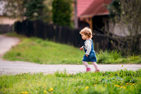 Seitenansicht eines kleinen Mädchens, das im Frühling auf dem Land spazieren geht. Raum kopieren. - HPIF20716