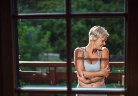 Vorderansicht einer älteren Frau mit Sport-BH, die im Sommer auf einer Terrasse steht. - HPIF20753