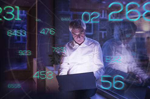 Futuristic numbers moving towards senior businessman working on laptop in office - UUF28766