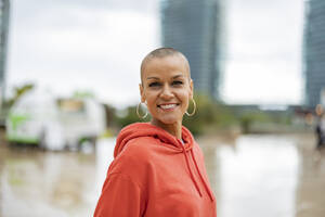 Mature woman with shaved hair in the city on a rainy day. Barcelona/​​Spain - JCCMF10397