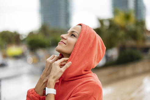 Smiling mature woman wearing hood in city - JCCMF10408