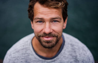 A portrait of happy handsome man standing outdoors, looking at camera. - HPIF20859