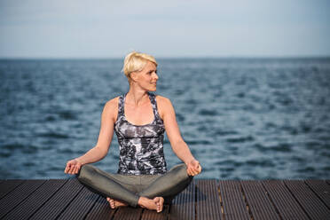 Front view portrait of young sportswoman doing yoga exercise on beach. Copy space. - HPIF20910