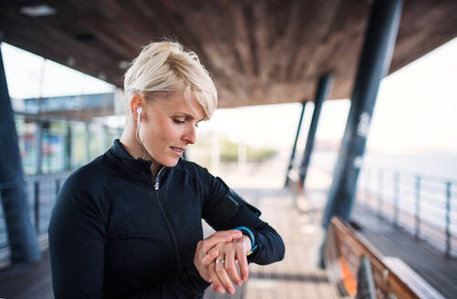 Ein Porträt einer jungen Sportlerin mit Smartwatch im Freien, die sich selbst aufzeichnet. - HPIF20918