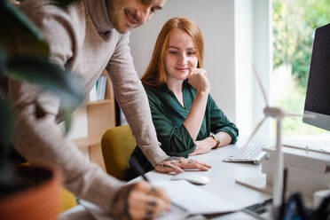 Junge Architekten mit Computer sitzen am Schreibtisch in Innenräumen im Büro, arbeiten. - HPIF20936