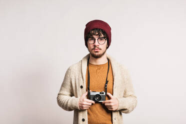 A young handsome man holding a camera in a studio. - HPIF21026