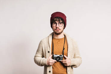Ein junger, gut aussehender Mann hält eine Kamera in einem Studio. - HPIF21026