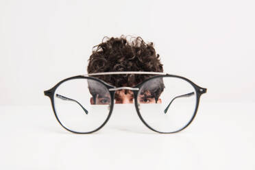 Head of a young man behind the eyeglasses on the table. Studio shot. Copy space. - HPIF21028