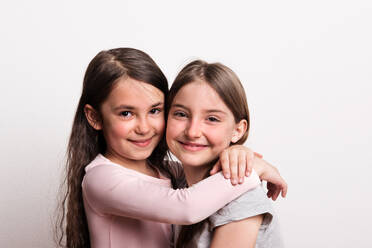 Two small cheerful girls standing in a studio, hugging. - HPIF21036