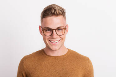 A happy confident young man in a studio, wearing glasses. - HPIF21058