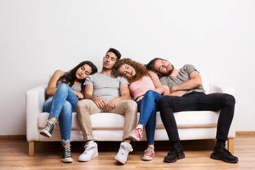 Porträt einer jungen Gruppe von müden Freunden, die auf einem Sofa in einem Studio sitzen und schlafen. - HPIF21065