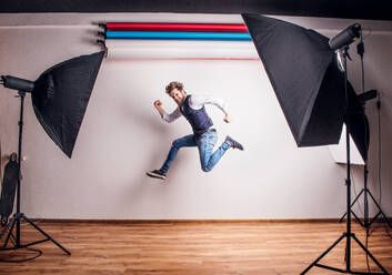 Portrait of a young handsome hipster man in a studio, jumping. Copy space. - HPIF21125