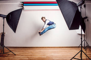 Portrait of a young handsome hipster man in a studio, jumping. Copy space. - HPIF21126